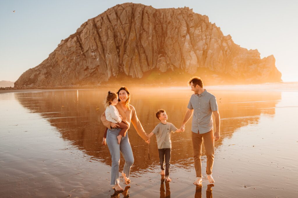 Family playing on the beach at Morro Bay with Morro Rock in the background during overcast light